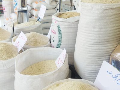 به گزارش برداشت اقتصادی به نقل از تجارت 100: مسعود پورباقی| قیمت برنج ایرانی با رسیدن به مرز هر کیلو 500 هزار تومان رکورد بی‌سابقه‌ای را در تاریخ معیشتی ایرانیان به ثبت رسانده است، خوراکی که تا یکی دو سال قبل پای ثابت سفره طیف وسیعی از خانوارها بود و اکنون اما در حال تبدیل شدن به خوراکی لوکس است که تنها تعداد کمی از خانوارها توان تهیه آن را دارند. جهش قیمتی که نه تنها محصول عوامل فصلی و اقلیمی مانند خشکسالی است، بلکه ریشه در ترکیبی از سیاست‌های ناکارآمد اقتصادی، دلالی سازمان‌یافته و فشارهای ژئوپلیتیکی دارد.